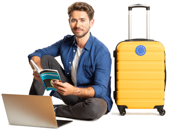 Man sitting next to a laptop and a suitcase, and reading a book