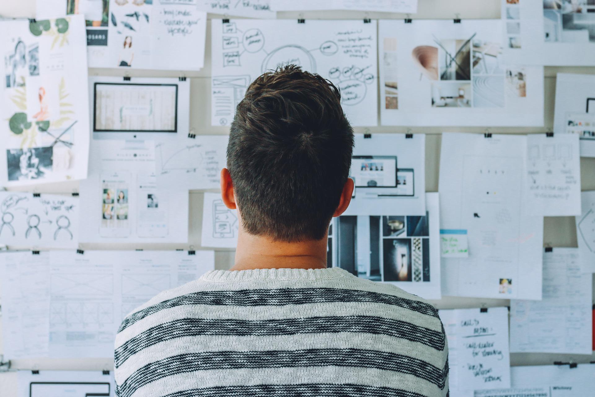 Man looking at a wall of papers