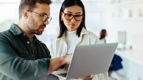 A man and woman look at a laptop and discuss