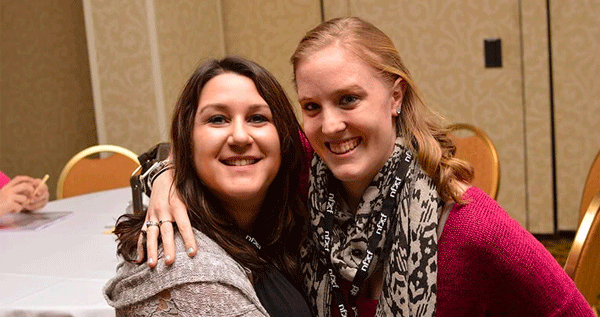 Two young women, one with Fragile X syndrome, with their arms around each other.