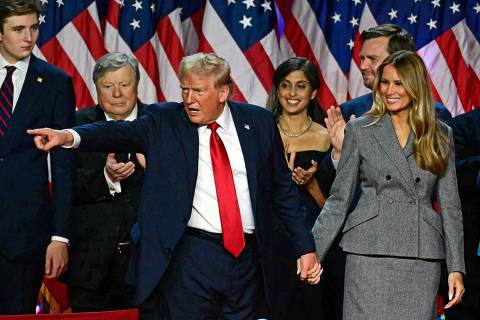 TOPSHOT - Former US President and Republican presidential candidate Donald Trump gestures at supporters after speaking as he holds hands with former US First Lady Melania Trump during an election night event at the West Palm Beach Convention Center in West Palm Beach, Florida, early on November 6, 2024. Republican former president Donald Trump closed in on a new term in the White House early November 6, 2024, just needing a handful of electoral votes to defeat Democratic Vice President Kamala Harris. (Photo by Jim WATSON / AFP)