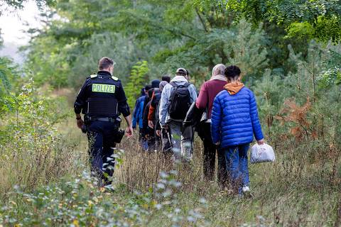 (FILES) An officer of the German Federal Police (Bundespolizei) escorts a group of migrants near Forst, eastern Germany on October 11, 2023, during a patrol near the border with Poland. Germany will extend temporary controls to all of its borders to crack down on irregular migration into the country, a government source told AFP on September 9, 2024. (Photo by JENS SCHLUETER / AFP)