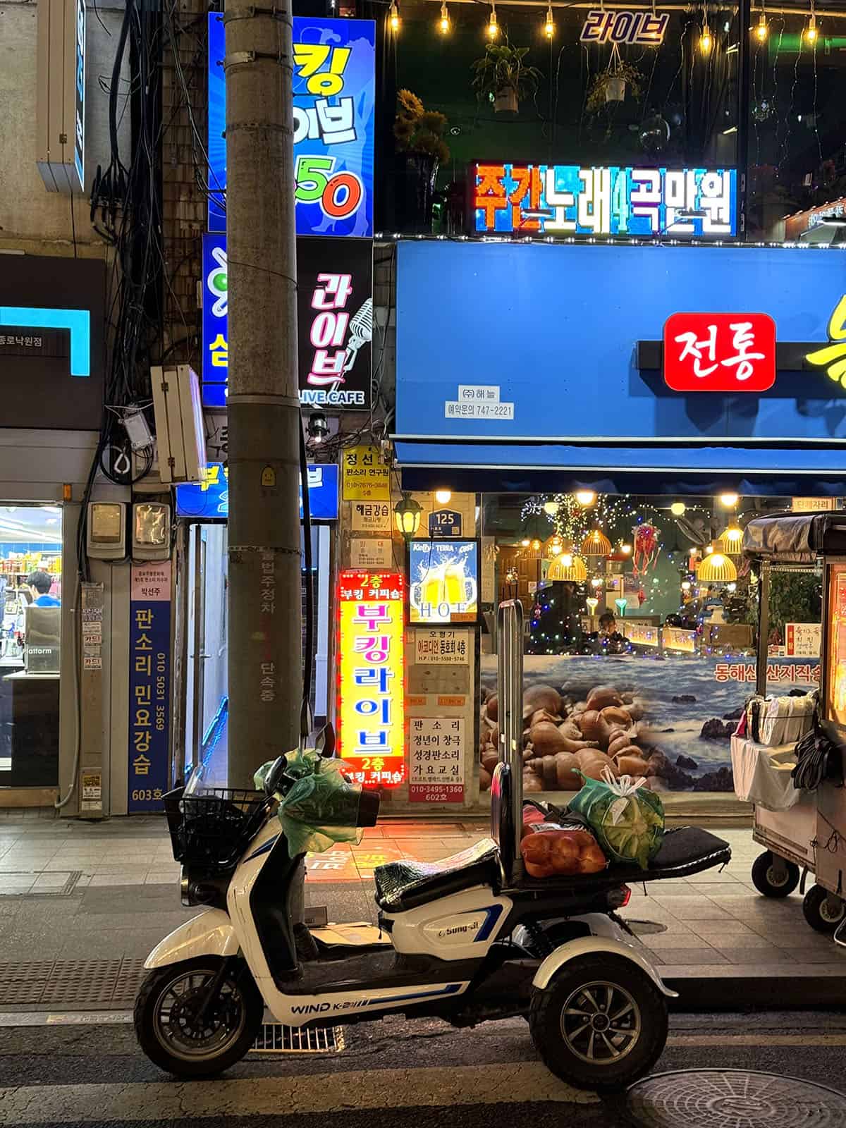 An image of a scooter in Seoul in front of a store lit up with neon signs