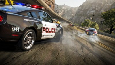 Need for Speed™ Hot Pursuit Remastered – kuvakaappaus poliisiautosta jahtaamassa autoja vuoristomaisemassa.