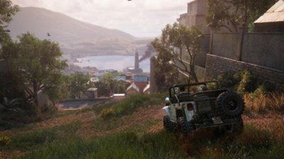 Captura de pantalla de ubicaciones de Uncharted 4 que muestra a Nathan y Sully en el jeep bajando por la ladera de una colina en dirección a un asentamiento 