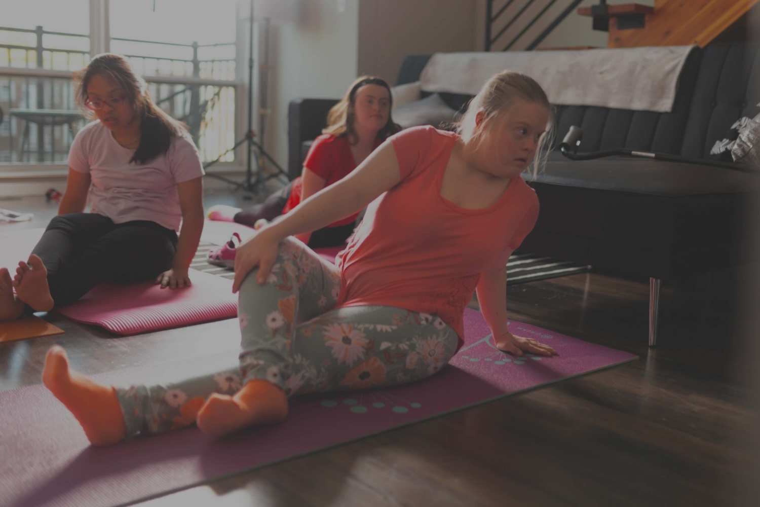 A group of three people practice yoga in a small studio.