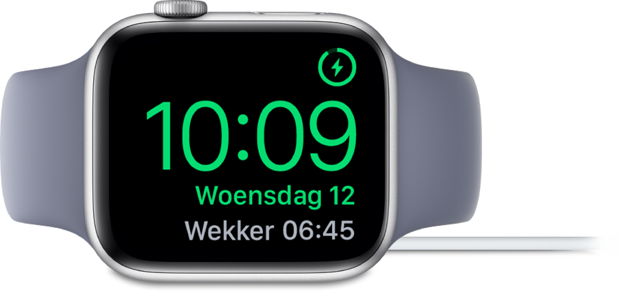 Een Apple Watch die op zijn kant ligt en is aangesloten op de oplader. Rechtsbovenin zie je het oplaadsymbool, en daaronder de actuele tijd en de tijd van de volgende wekker.