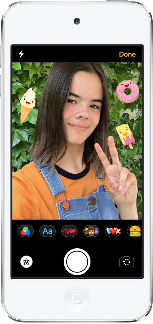 Layar efek Pesan. Bagian atas layar menampilkan bingkai kamera depan. Stiker iMessage ada di sekitar subjek di bingkai. Di bawah bingkai, dari kiri ke kanan, adalah tombol filter, teks, bentuk, Memoji, Animoji, dan app iMessage. Di bagian bawah layar, dari kiri ke kanan, terdapat tombol Efek, Rana, dan Pemilih Kamera.