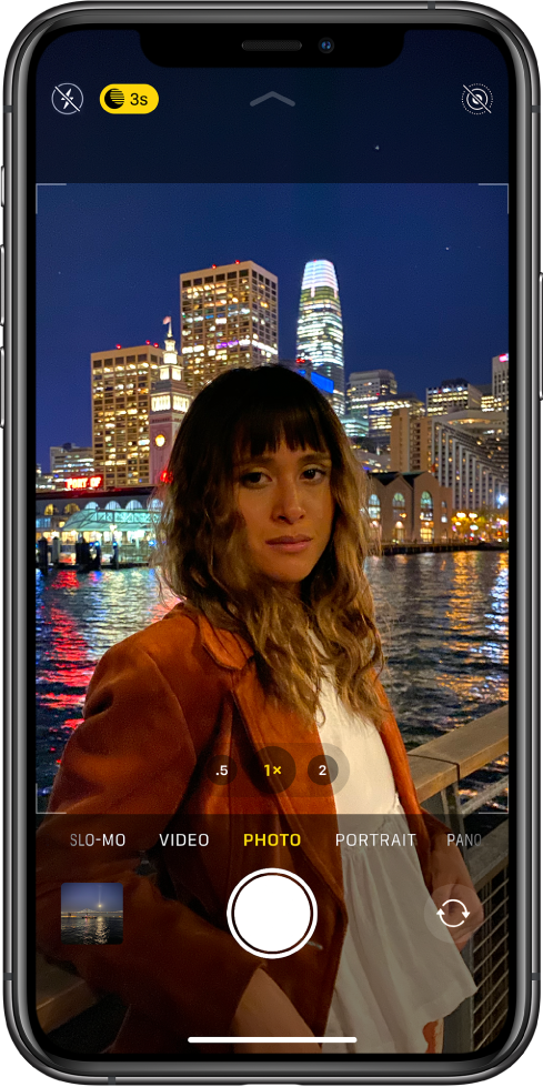 Camera in Photo mode. Buttons for flash and Night mode appear in the top-left corner of the screen. The flash button is turned off and the Night mode button is active. The Live photo button is in the top-right corner. The photo and video viewer is in the bottom-left corner. The Shutter button is at the bottom center, and the camera chooser button is in the bottom-right corner.