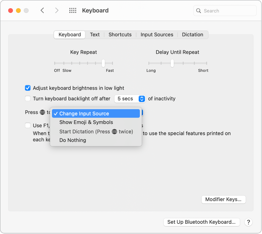 Panel preferensi Papan Ketik dengan menu pop-up menampilkan pilihan untuk tombol Function/Globe: Ubah Sumber Input, Tampilkan Emoji & Simbol, Mulai Dikte, dan Jangan Lakukan Apa-Apa.