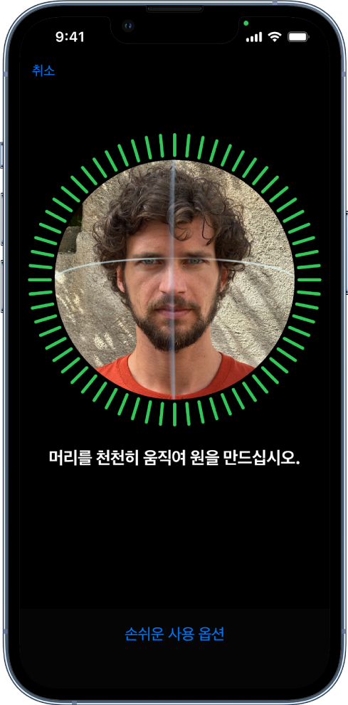 Face ID 인식 설정 화면. 원형 프레임 안에 얼굴이 있는 화면이 표시됨. 아래에는 사용자에게 천천히 머리를 움직여 원을 완성하라는 지침이 표시된 텍스트가 있음. 화면 하단 근처에 손쉬운 사용 옵션 버튼이 표시됨.