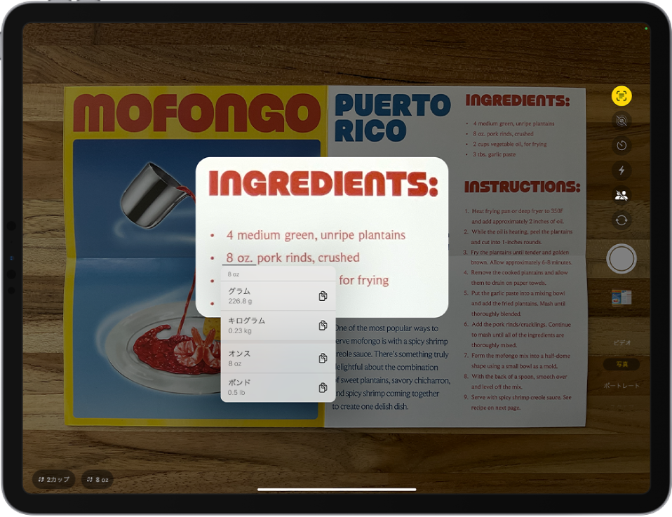 「カメラ」画面。カメラフレームにレシピが表示されています。メニュー内のテキストが選択され、下線のついたテキストに8オンスの換算オプションが表示されています。画面下部には、2カップと8オンスを換算するクイック・アクション・ボタンがあります。