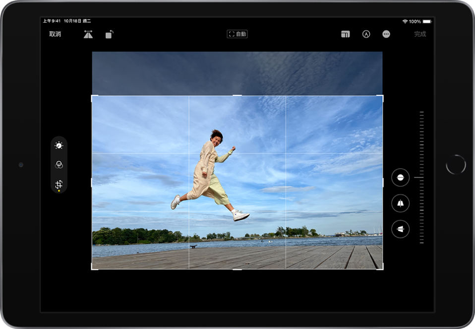 橫向方向的 iPad。螢幕中央為處於「編輯」模式的照片，格線和裁切框覆疊在照片上。螢幕左側為「調整」、「濾鏡」和「裁切」按鈕；已選取「裁切」按鈕。螢幕右側為裁切增強選項和強度滑桿。螢幕左上角為「取消」、「翻轉」和「旋轉」按鈕。螢幕右上角為「顯示比例」、「標示」和「完成」按鈕。