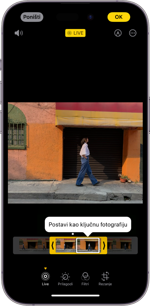 Live Photo zaslon s Live Photo u sredini. Ispod fotografije nalazi se preglednik kadrova s aktivnom tipkom Postavi kao ključnu fotografiju. Na bilo kojem kraju preglednika kadrova nalaze se dvije strelice koje vam omogućuju odrezati Live Photo. Pri dnu zaslona nalaze se tipke Live, Prilagodi, Filtri i Rezanje. Odabran je tipka Live. Tipka Poništi nalazi se u gornjem lijevom kutu zaslona, a tipka OK je u gornjem desnom kutu zaslona. Također na vrhu zaslona, slijeva na desno, nalaze se tipke Isključi zvuk, Live, Označavanje i Plugini.