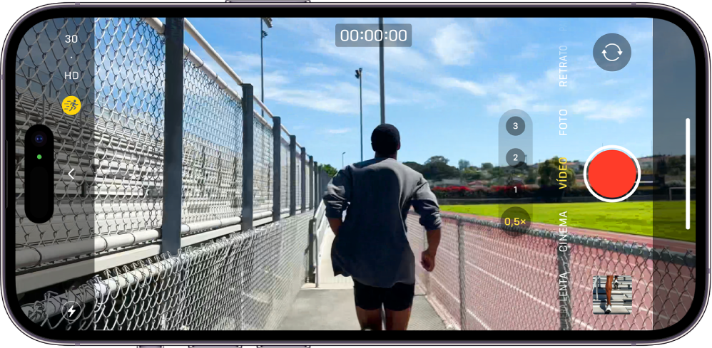 O iPhone está virado horizontalmente. O app Câmera está aberto no modo Vídeo. Há uma pessoa correndo na moldura da câmera. O botão Flash encontra-se no canto inferior esquerdo da tela. O botão Controles da Câmera encontra-se na parte central esquerda da tela. No canto superior esquerdo há botões rápidos para alternar a resolução de vídeo e a taxa de quadros. O botão de Ação está ativado no canto superior esquerdo. No lado direito estão, de cima para baixo, o botão Seletor de Câmera Traseira, o botão Gravar e o botão Visualizador de Foto e Vídeo. No visor, uma pessoa está correndo.