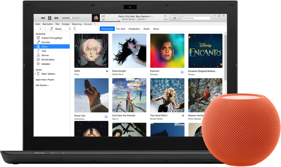 Ein PC mit iTunes auf dem Bildschirm und einem HomePod mini in der Nähe