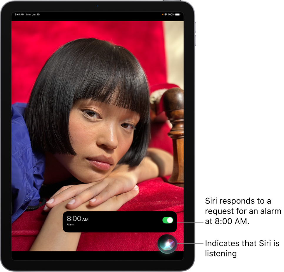 An iPad screen. Near the bottom of the screen, a notification from the Clock app shows that an alarm is turned on for 8:00 a.m. An icon below the notification indicates that Siri is listening.