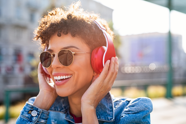 Smiling young woman with a blue jacket and red headphones.  