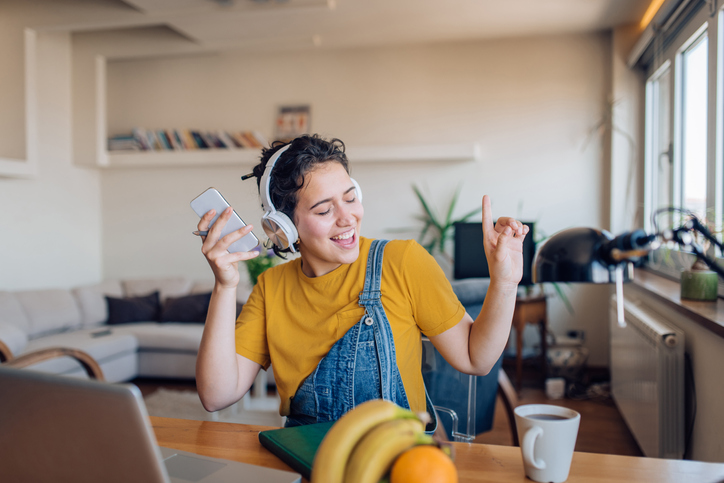 Young woman listening to music on headphones and singing along. 