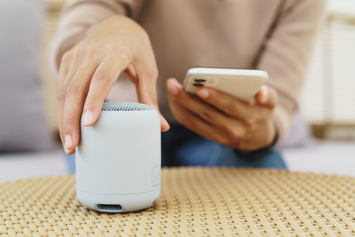 Woman holding a phone and a bluetooth speaker