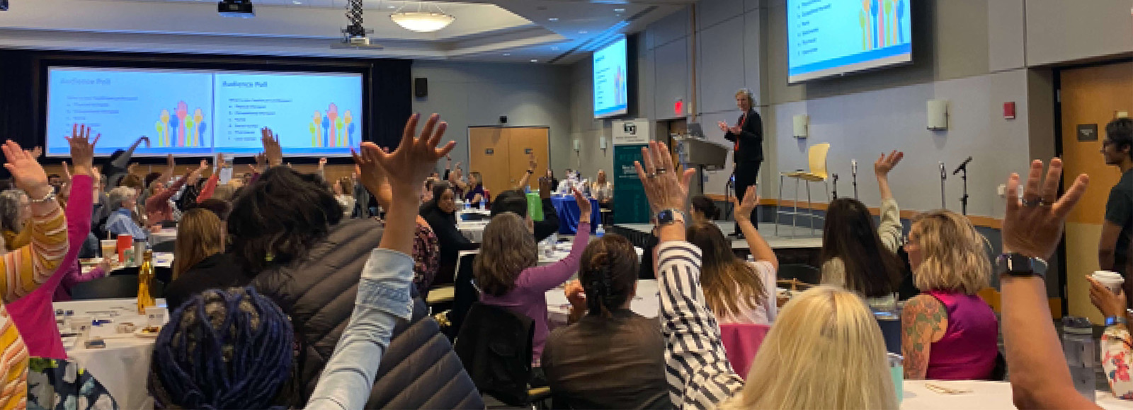 A crowd raising their hands at a conference.