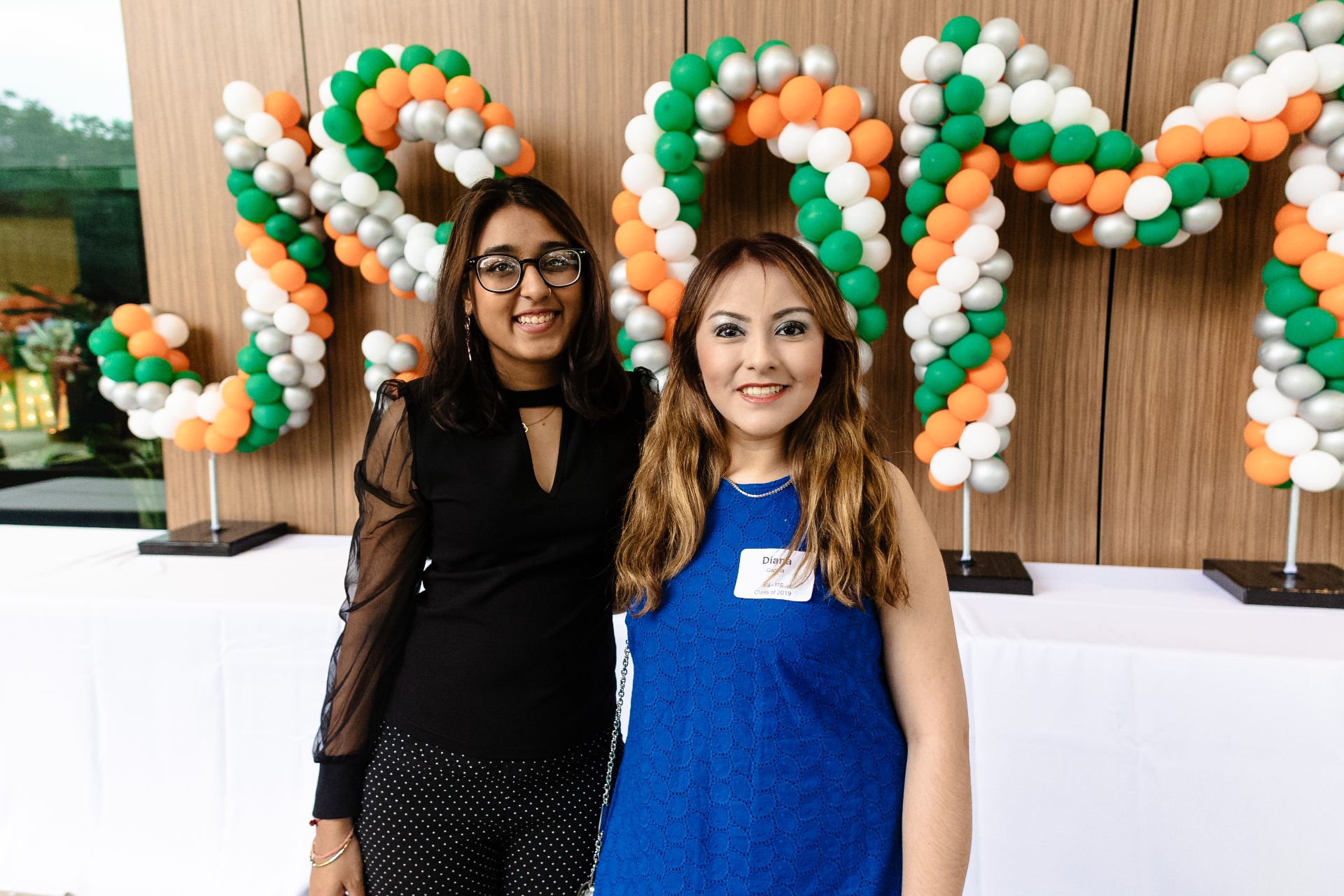 Two JSOM Alumni against a background that has a JSOM balloon arc