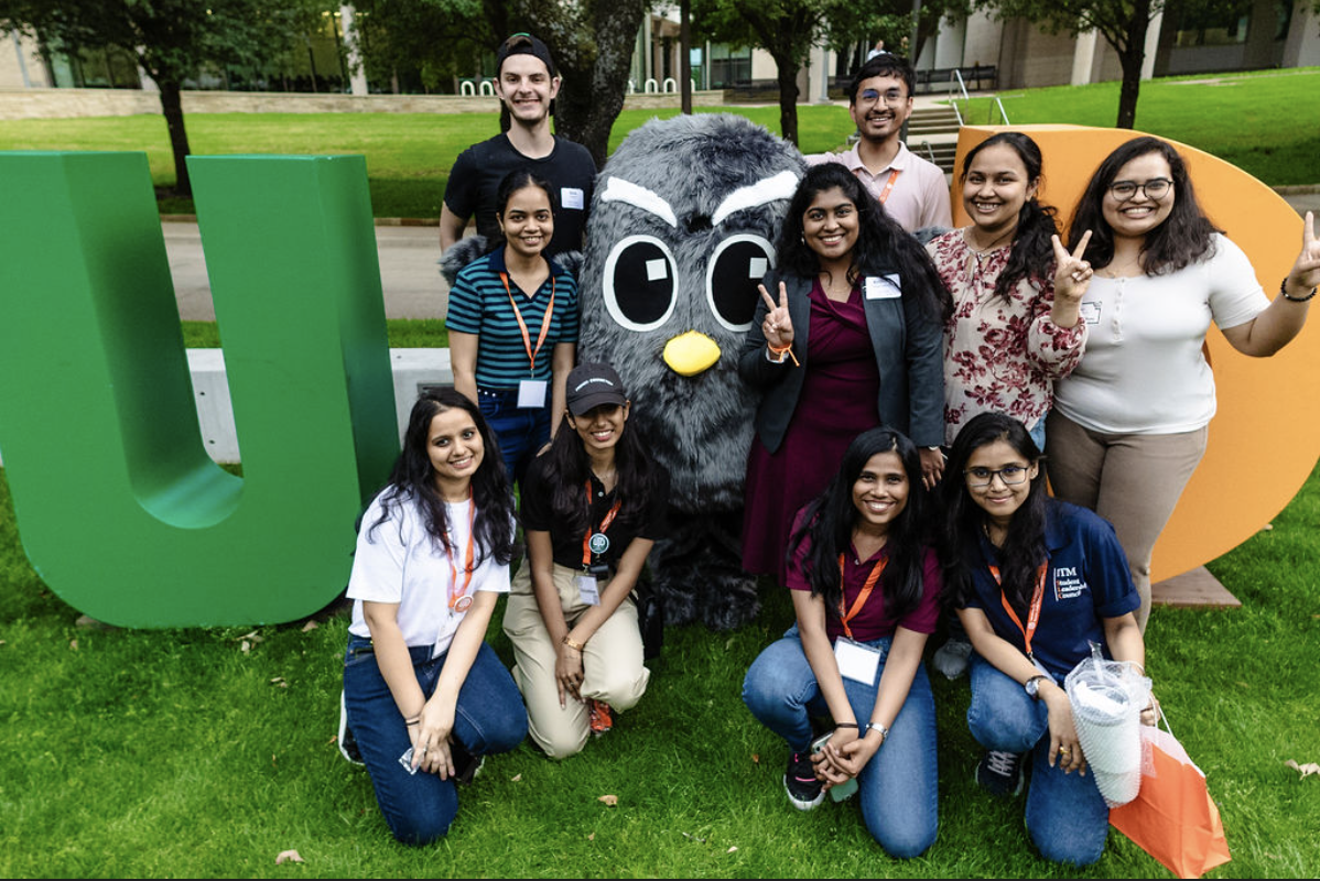 students posing next to OWLIE against a UTD cutout