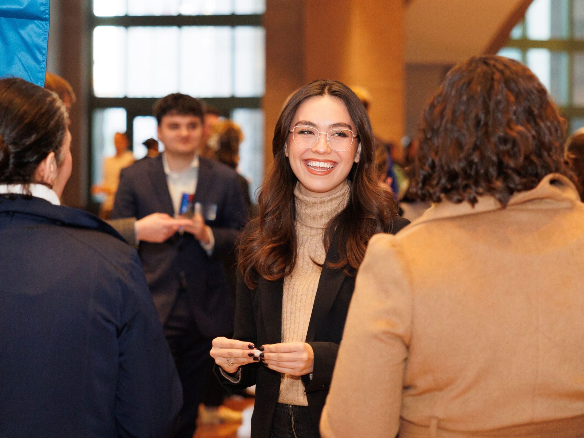 Student standing in room full of people at a reception