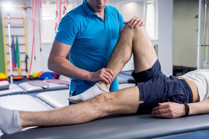 Massage du genou par un physiothérapeute dans une salle de sport.