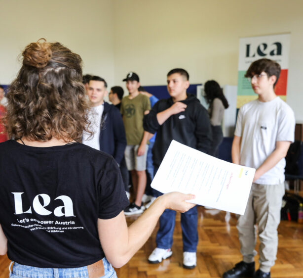 Workshop-Leiterin im LEA T-Shirt im Vordergrund, vor ihr Gruppe junger Teilnehmenden