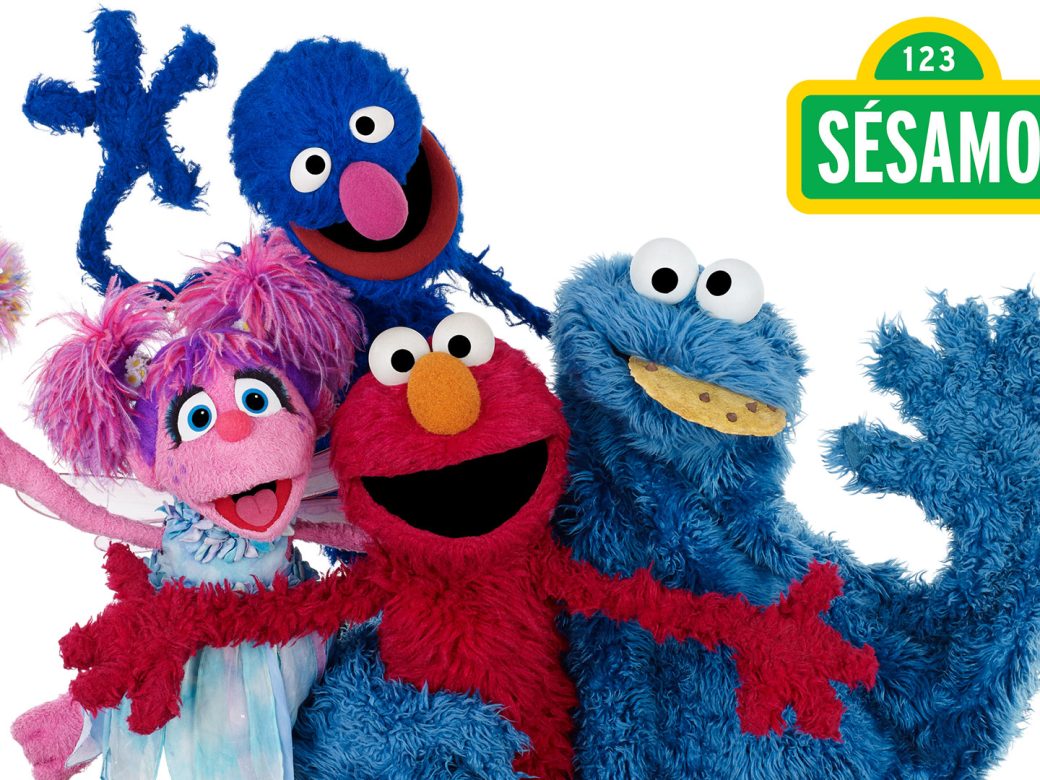 Abby, Grover, Elmo, and Cookie Monster pose and wave at us.