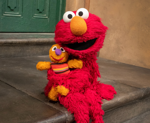 Elmo sits on the stoop of 123 with Baby David.