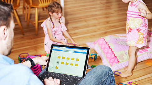 a person using oneDrive on a laptop watching his two daughters play together