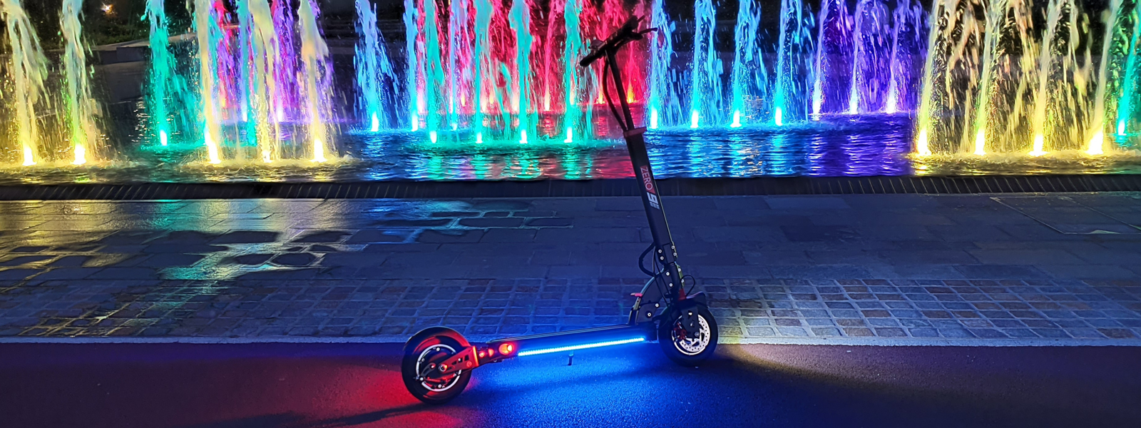 A scooter in front of a colorful fountain