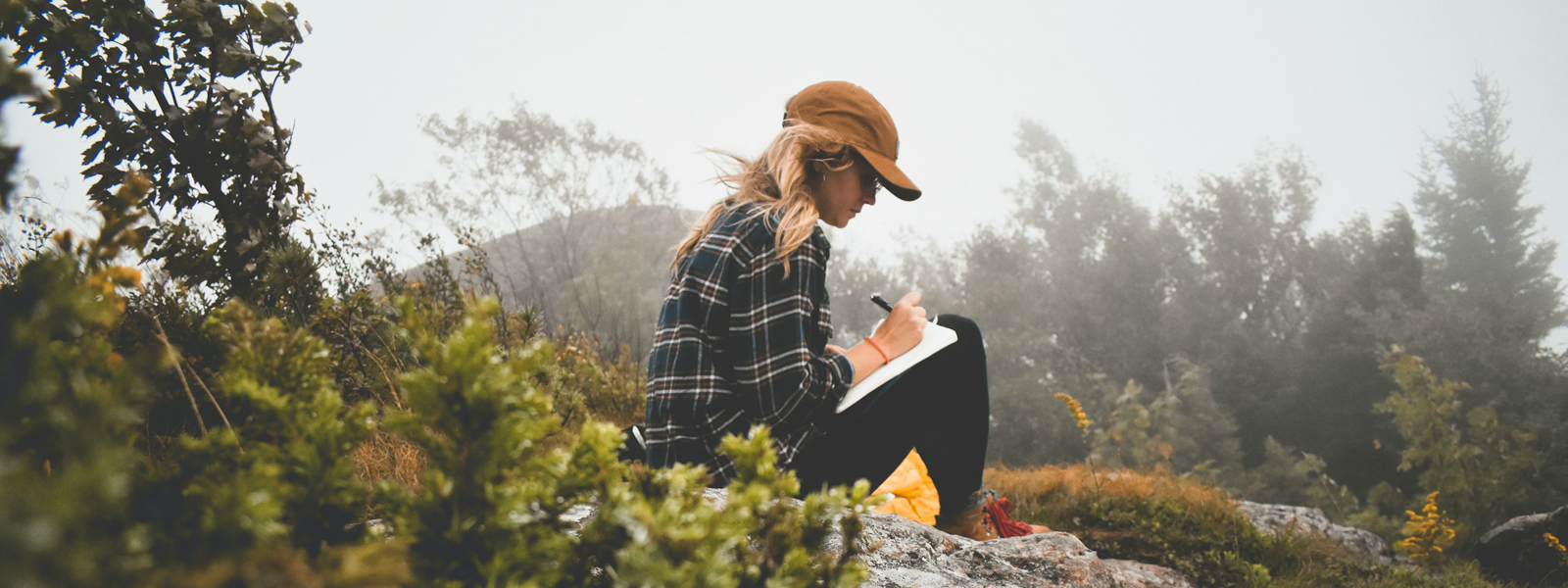 Woman sitting on a rock writing in a journal