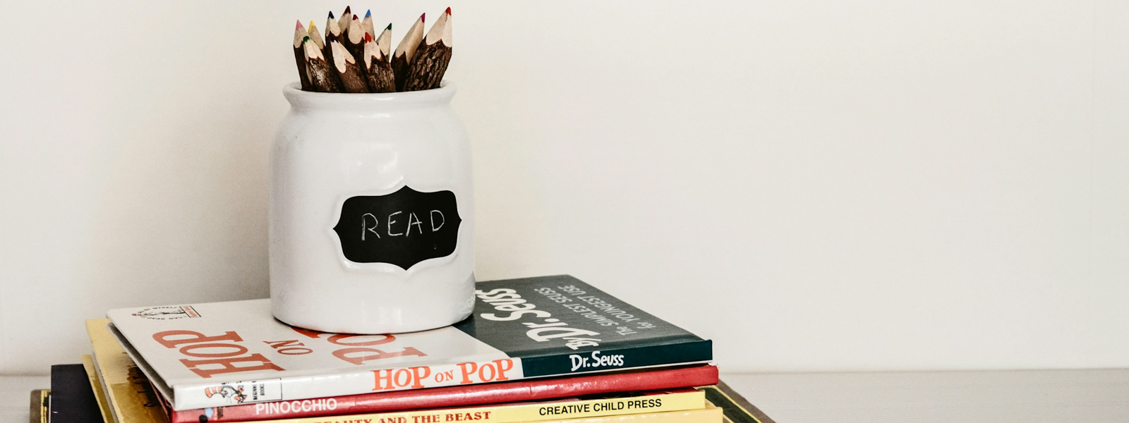 A mug with pencils on top of a stack of books