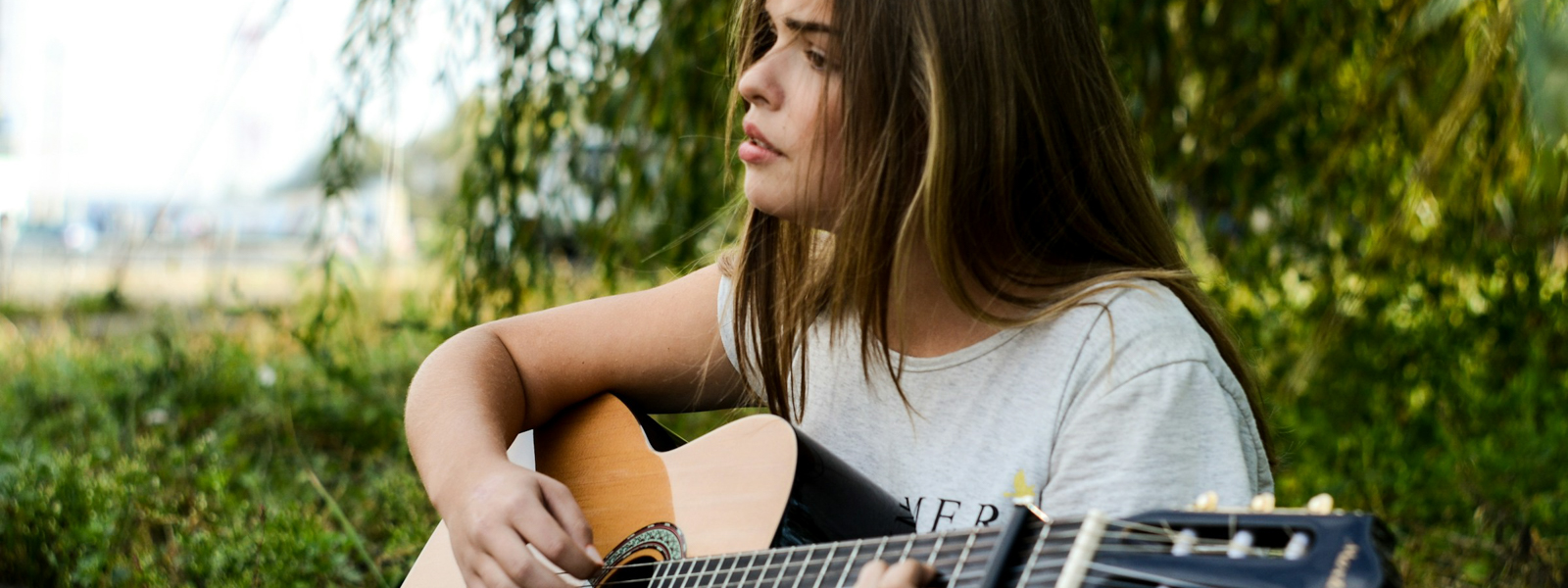 Woman outside singing while playing guitar