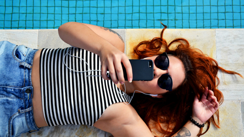 A woman lying on the ground looking at her cell phone