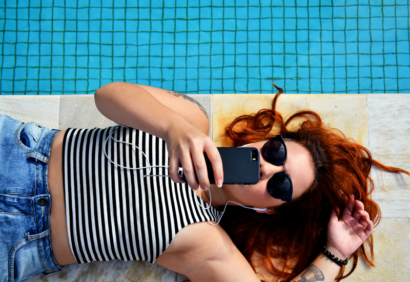 A woman lying on the ground looking at her cell phone