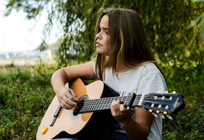 Woman outside singing while playing guitar