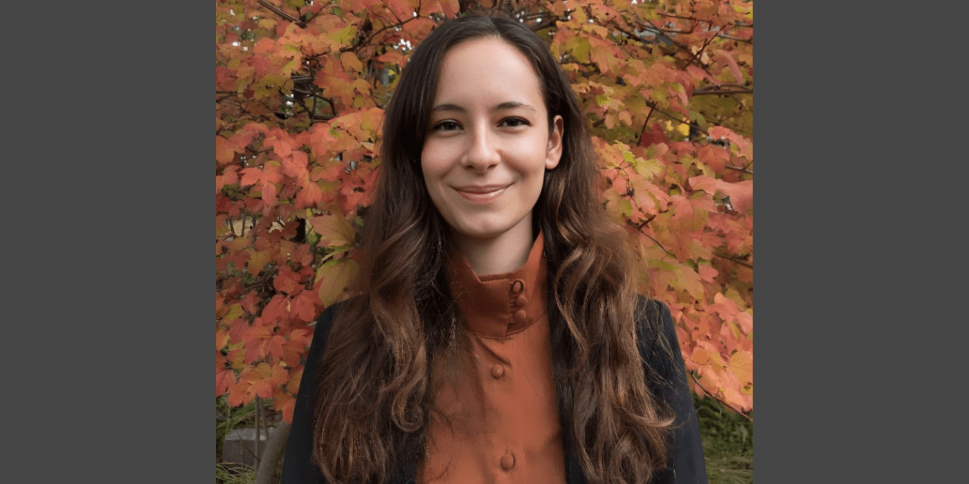 Dr. Buse Gonul stands in front of autumn leaves.