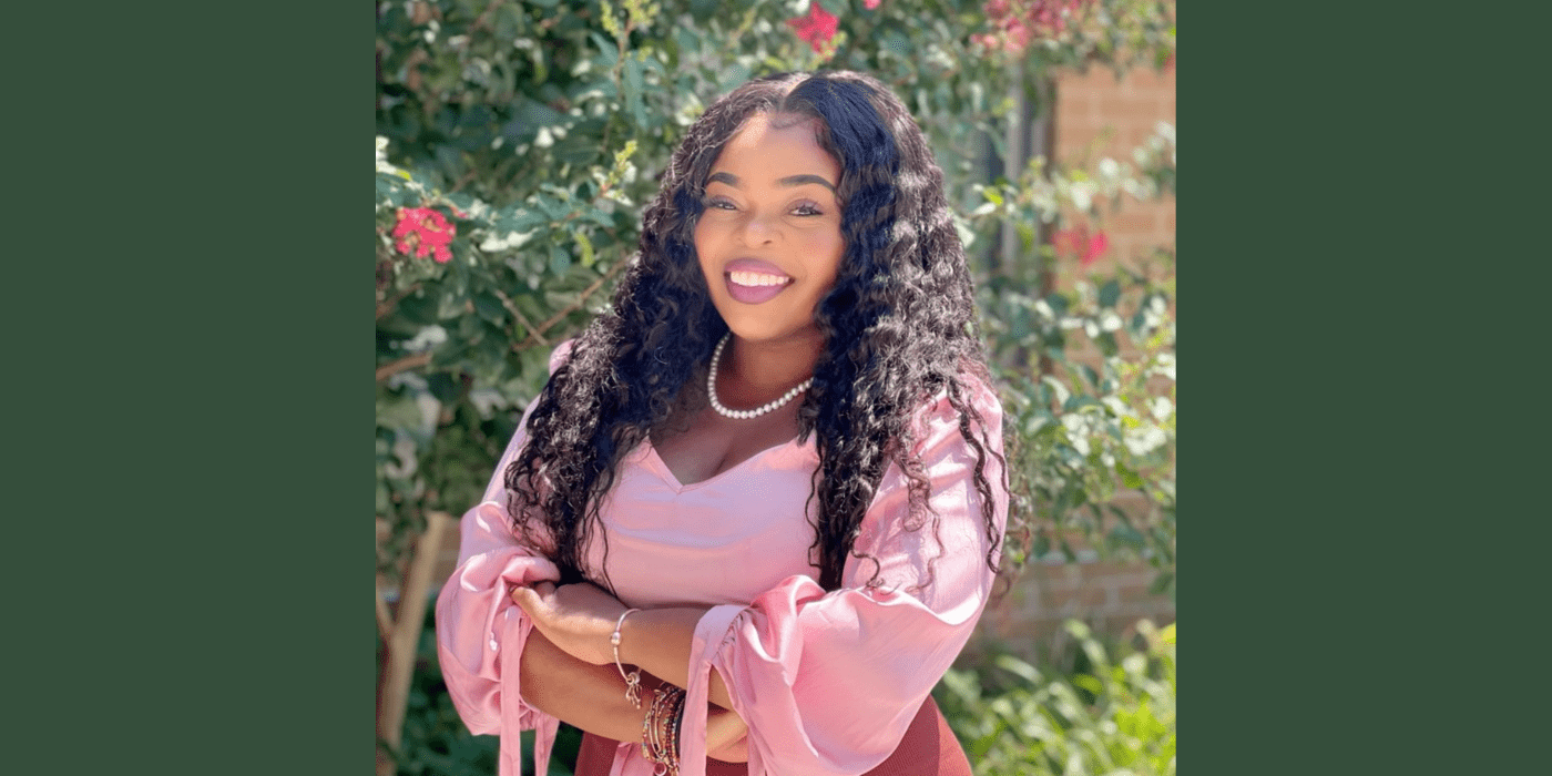 Samara Toussaint wearing a pink blouse standing in front of a tree