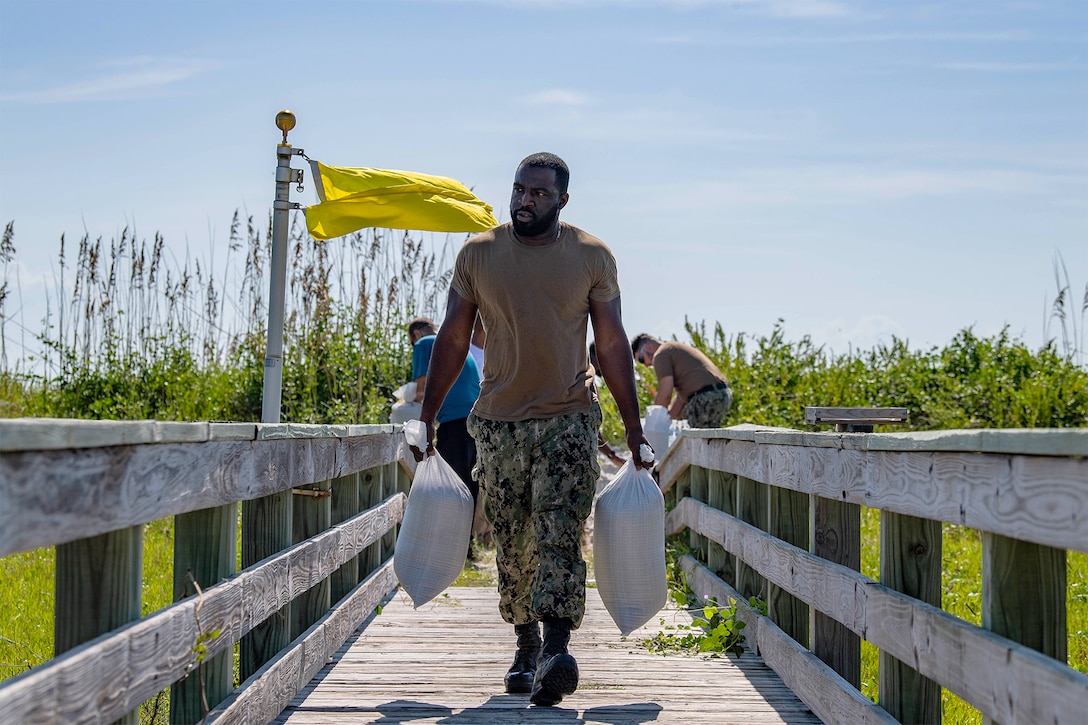 Navy Petty Officer 1st Class Carl Miller carries sandbags in preparation for Hurricane Dorian.