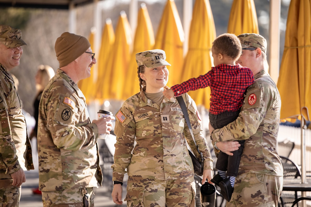 Several guardsmen interact with a child, while one guardsman holds the child.