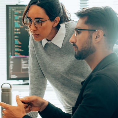 Two employees working at a computer in an office setting