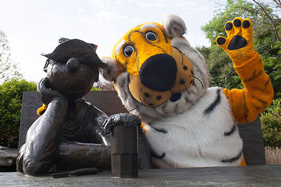 Truman Tiger mascot waving with an arm around the Beetle Bailey statue