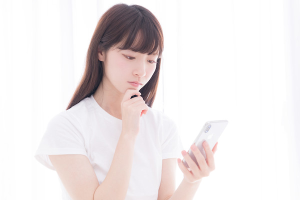 考えながらスマホを見る女性