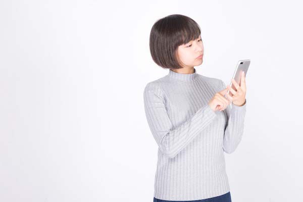 スマホを見ながら首を傾げる女性