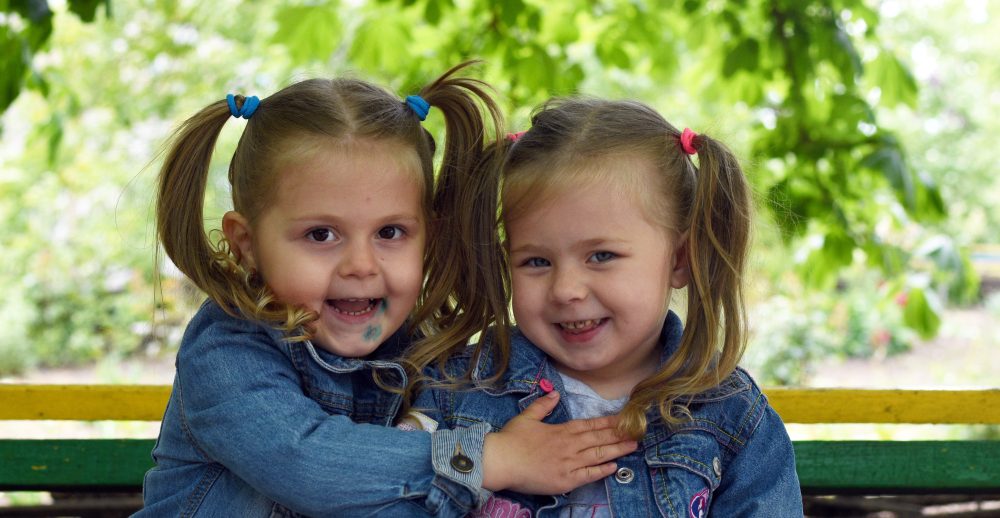 Liliana and Diana, 3, sit on bench at the Amici di Bambini centre