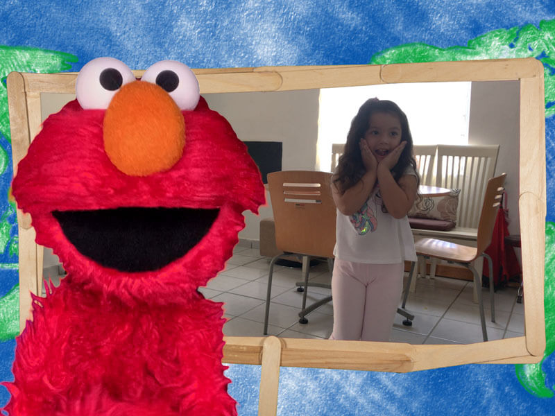 Elmo sonria y una niña al fondo baila